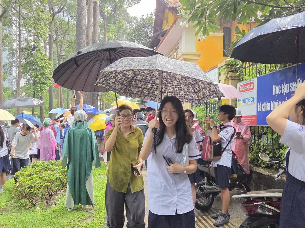 Kandidater vid Trung Vuong High Schools examenscenter går iväg i ösregnet. Foto: THU TAM