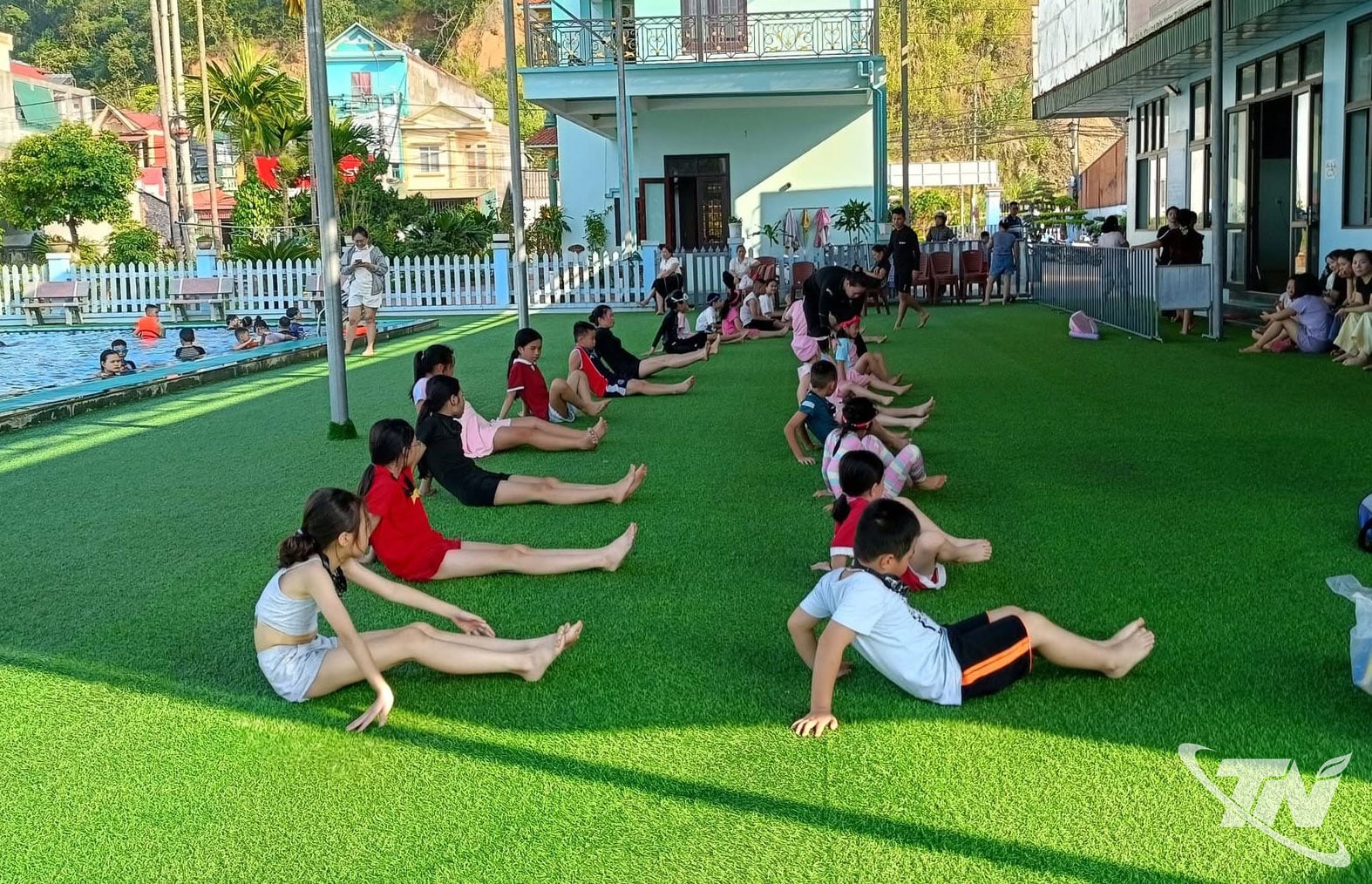 Các học viên khởi động trước khi xuống nước tại lớp học bơi ở Bể bơi Nhi Đồng, phường Đức Xuân.