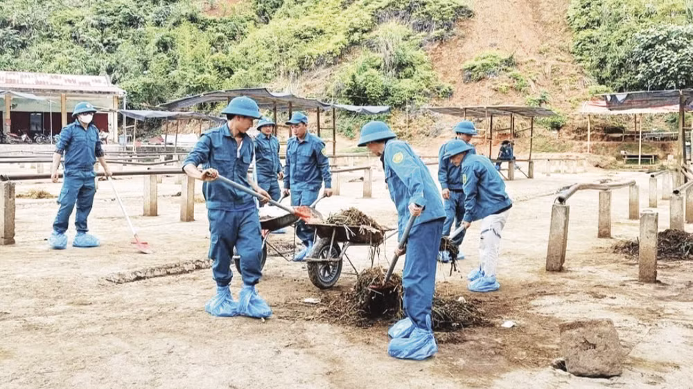 Dân quân tự vệ xã Nghiên Loan dọn dẹp, vệ sinh môi trường tại chợ trâu, bò. (Ảnh: SƠN LÂM)