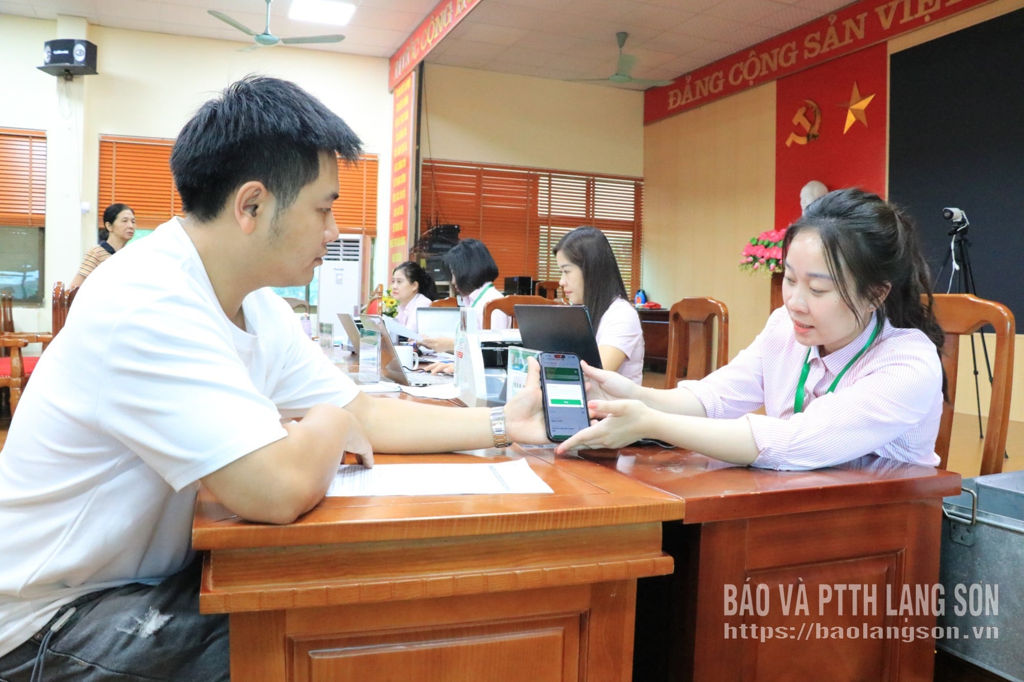 Officials from the Provincial Branch of the Vietnam Social Policy Bank guide customers on using the VBSP SmartBanking application.