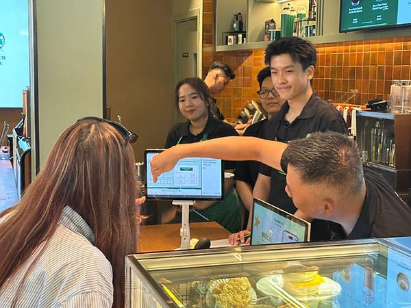 Egy hallássérült alkalmazott vezeti végig a vásárlókat a rendelési folyamaton egy képernyőn keresztül a Signing Store Cao Thắng üzletben.